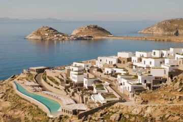 Cali Mykonos birds-eye view over very long infinity pool, whitewashed buildings and Aegean Sea