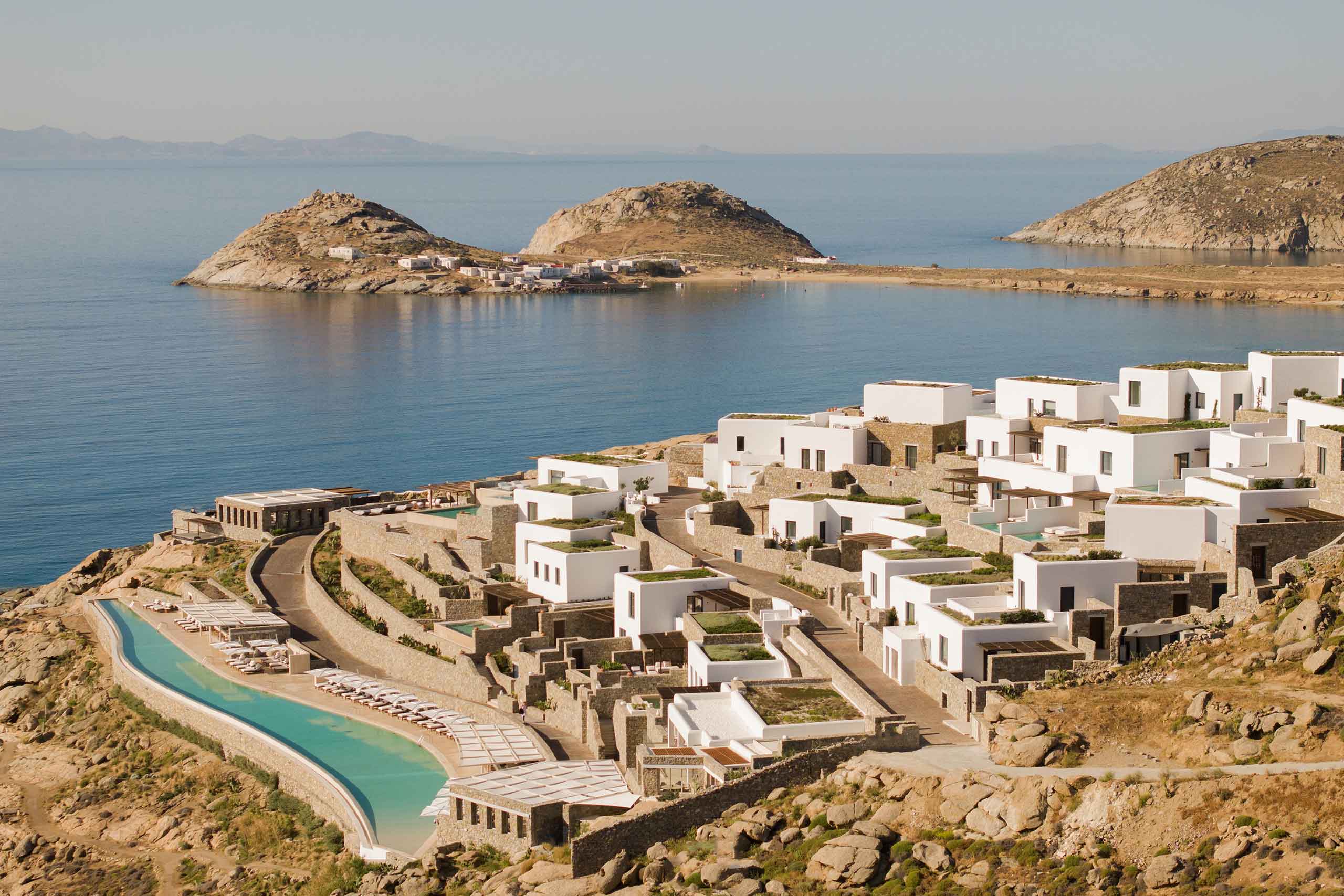 Cali Mykonos birds-eye view over very long infinity pool, whitewashed buildings and Aegean Sea