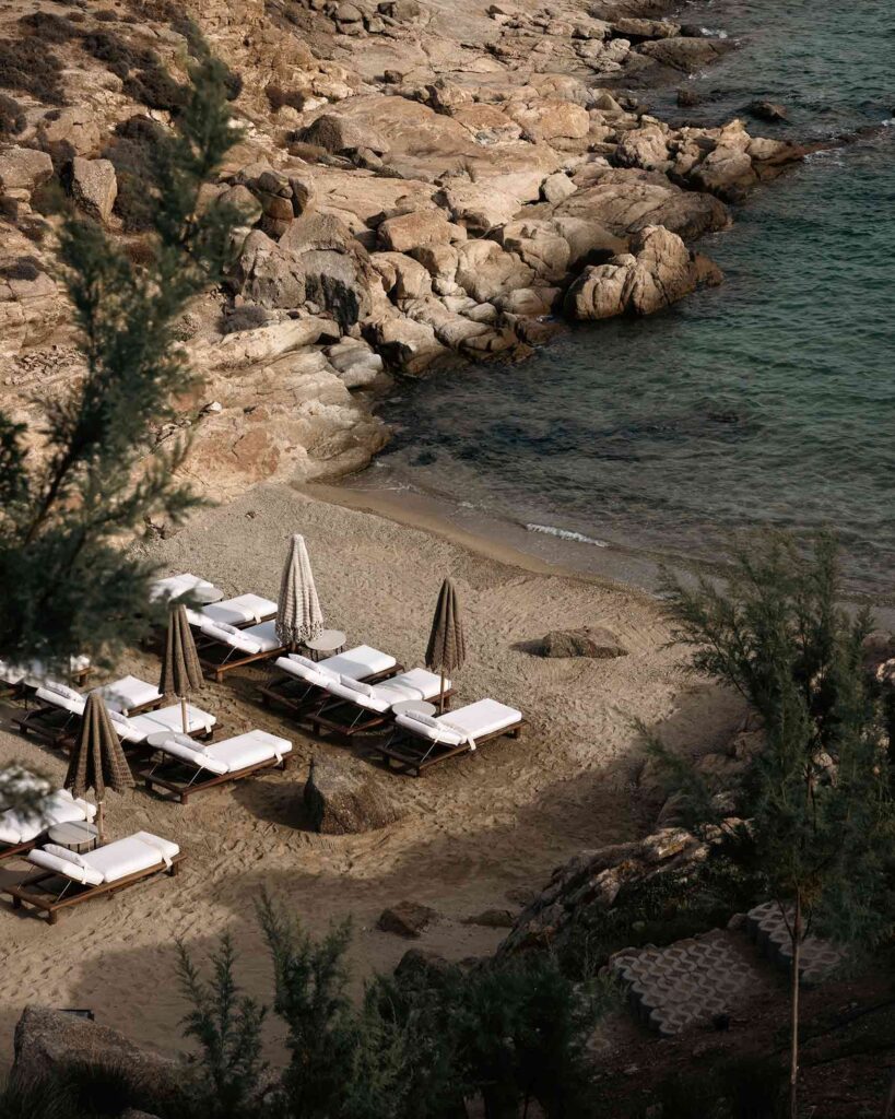 Small, sandy beach cove, with white sunloungers