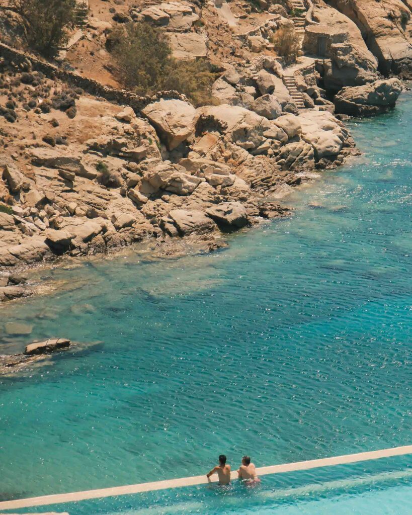 Two men look out over an infinity pool to the sea