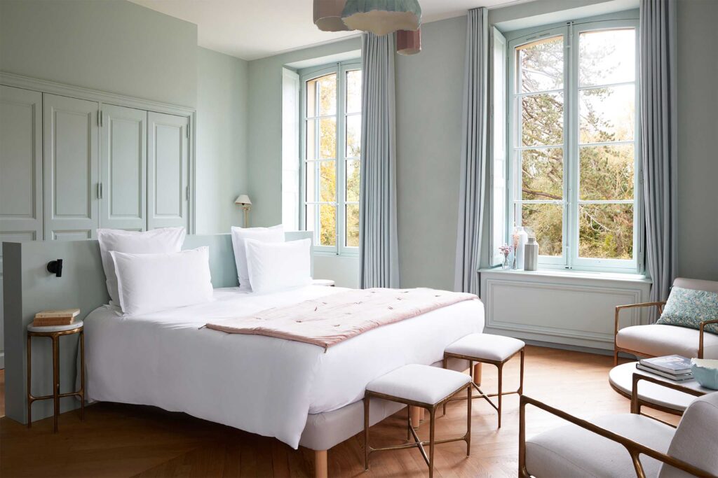 A cosy and bright bedroom with pale blue walls at Domaine de Primard Guainville.