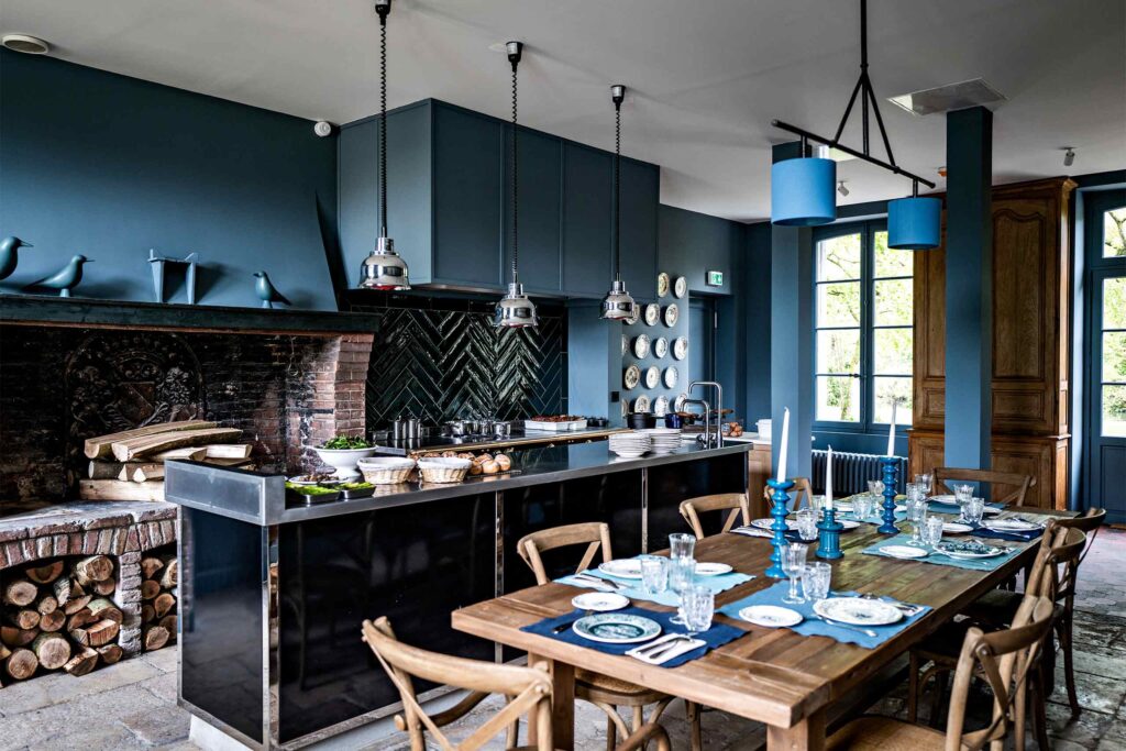 A rustic but delicate-looking kitchen with dark blue walls at Domaine de Primard Guainville.