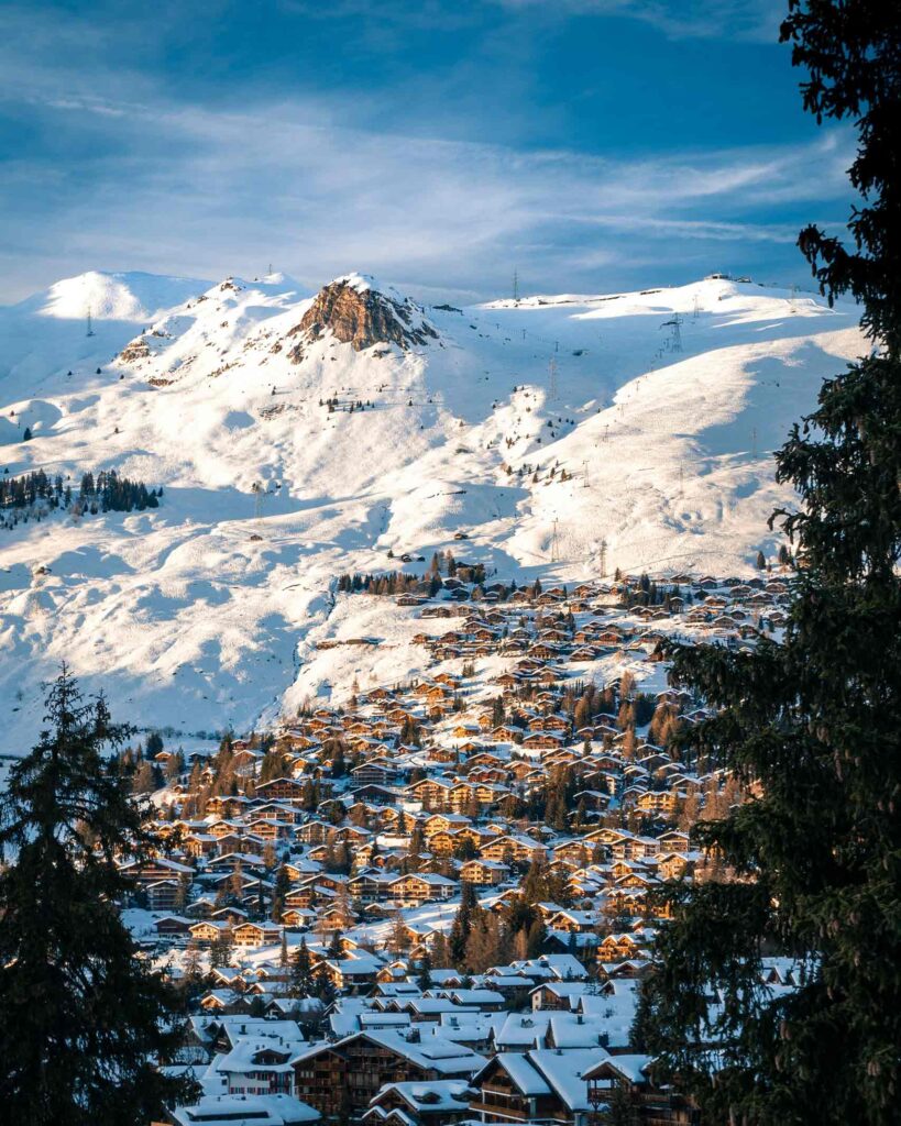 Aerial view of the village of Verbier at the foot of a snowy mountain in the Swiss Alps. A membership to Club Avandra, which takes female travellers here, belongs on any experiential gift guide