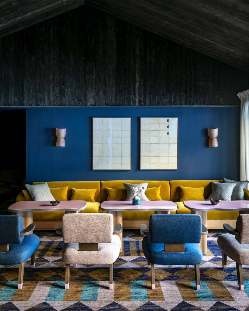 Colourful and contemporary seating area with a blue wall and a yellow sofa at Hotel Le Coucou, Méribel, France
