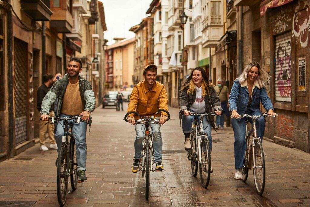A gay and lesbian couple ride bikes through Bilbao.