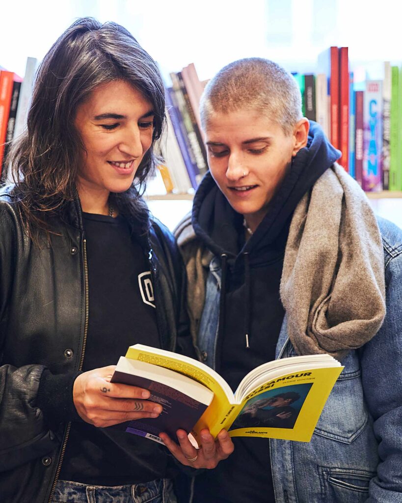 Marie Patouillet and Soraya Garlenq flip through the pages of a book together in Paris, France
