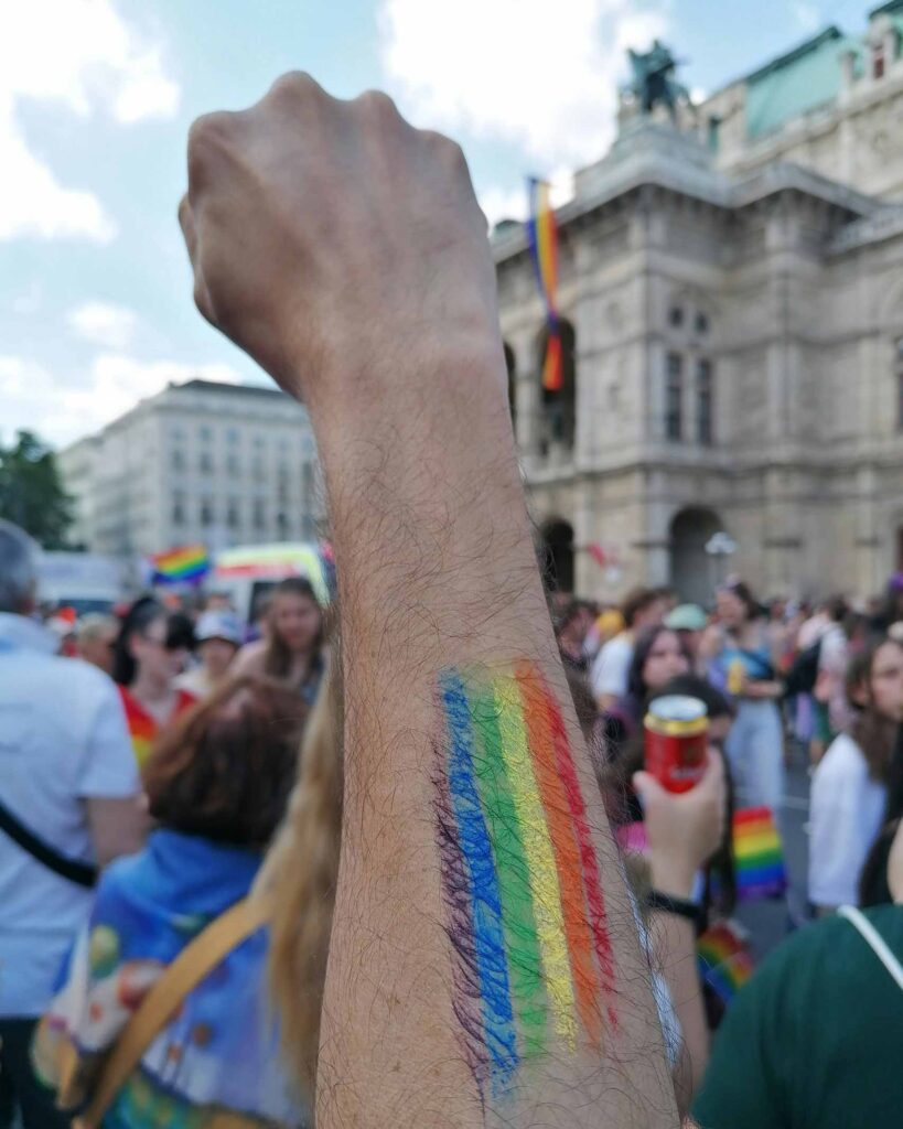 LGBTQ+ solidarity fist with rainbow coloured paint on arm