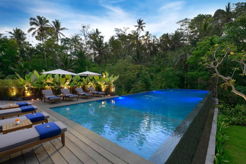 Poolside loungers and parasols by a large outdoor swimming pool in Bali, Indonesia