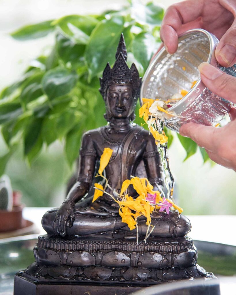 A Buddha statue is being purified with water during Songkran celebrations