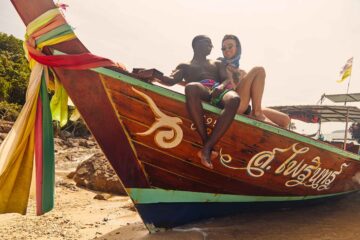 Gay couple sitting on the front of Thai longboat