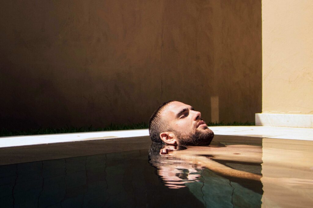 A man relaxes in a pool, an example of wellness tourism